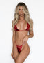 Model wearing the Heartbreaker Bikini Set in ruby red, showing the front view with a metallic shine.